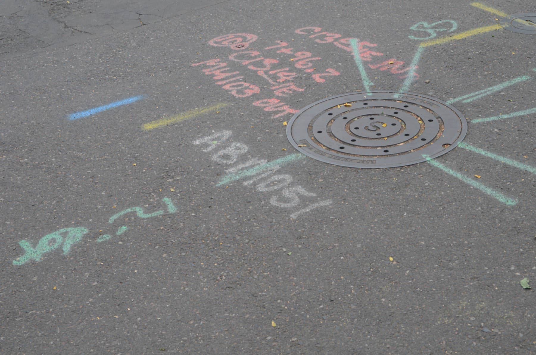 Manhole cover set into new pavement with construction markings around it