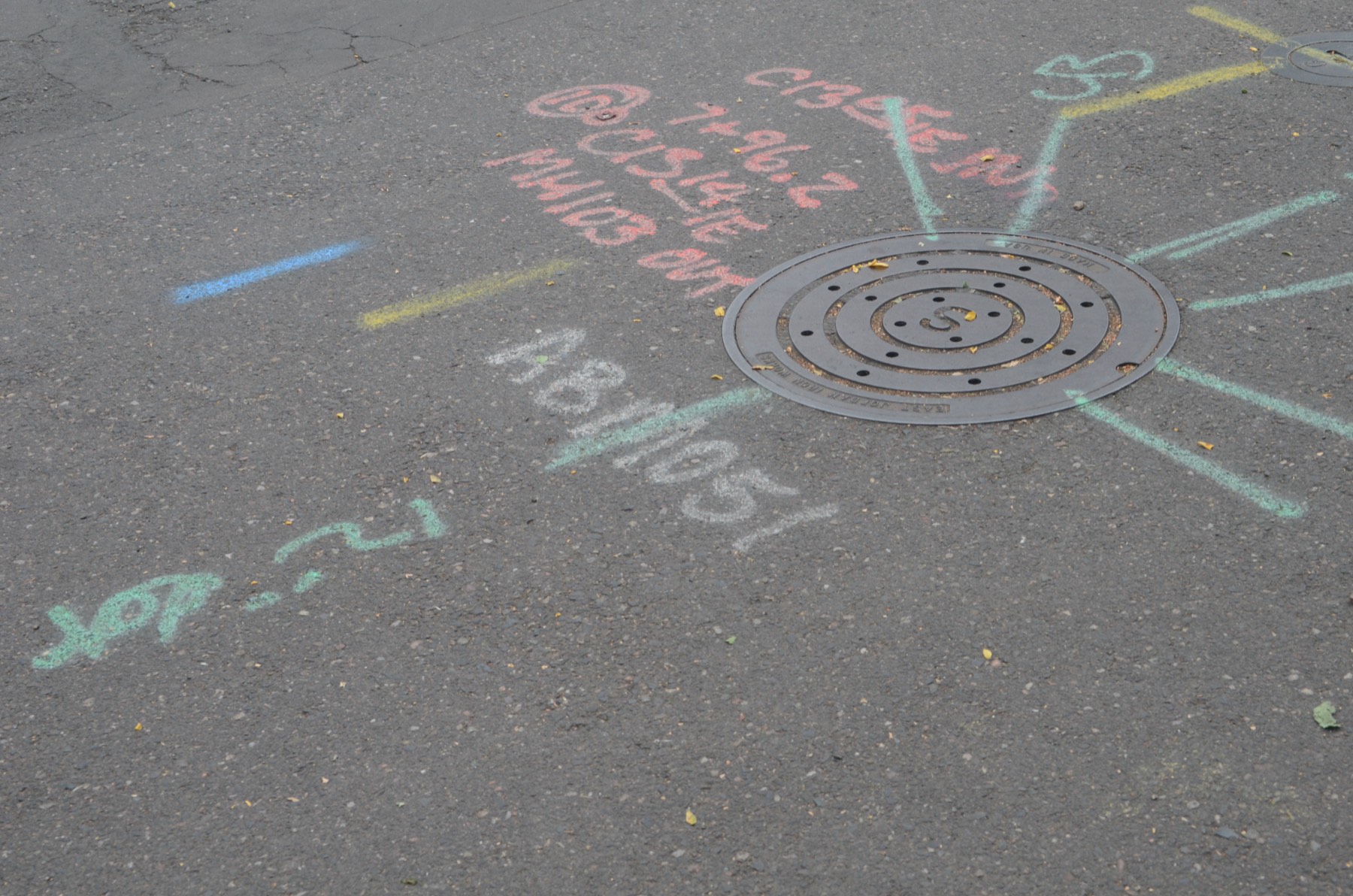 Manhole cover set into new pavement with construction markings around it